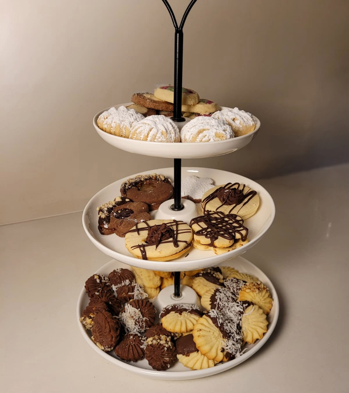 Round platter of assorted Middle Eastern desserts — Kahk with powdered sugar, chocolate-dipped petit four, different shaped Ghorayeba, Laksheir and Nashader biscuits